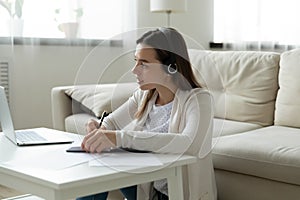 Focused woman in headphones watch webinar on laptop writing notes photo