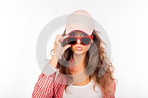 Young serious girl in pink hat touching her glasses and pouting