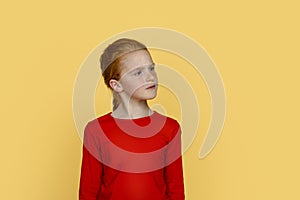 Young serious girl with red hair opposes something against  blue background