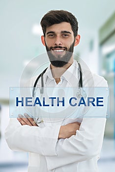 Young serious handsome bearded doctor with white coat and stethoscope.