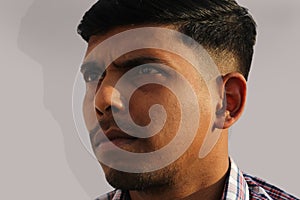 Young serious looking Indian man close up face portrait on isolated background.