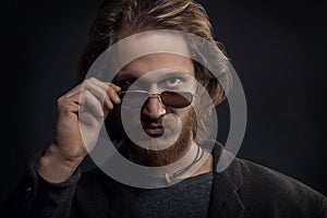 Young serious man with beard and moustache looking over his sunglasses