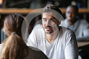 Young serious man having conversation with woman girlfriend in cafe