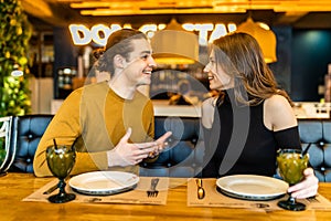 Young serious man having conversation with woman girlfriend sit at cafe table