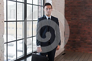 Young serious man standing near office window. Manager director boss entrepreneur employer.