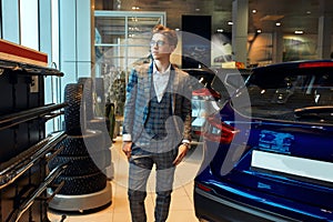 Young serious man walking at the motor show