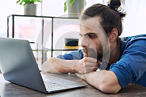 Young serious man working, studying using laptop sitting in coworking cafe