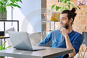 Young serious man working, studying using laptop sitting in coworking cafe