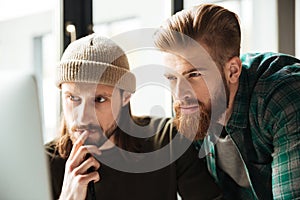 Young serious men colleagues in office using computer