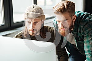 Young serious men colleagues in office using computer