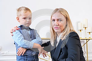 A young serious woman blonde in a black blazer and a little boy portraying a businessman