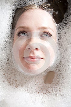 Young serious woman enjoys the bath-foam
