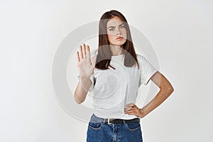 Young serious woman telling no, extend palm in stop sign and frowning disappointed, refuse or prohibit something