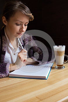 Young serious woman thinking with pen and open notebook. Thoughtful girl portrait. Journalist and writer concept. Business lifesty