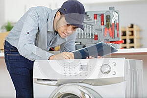 Young serviceman assessing washing machine