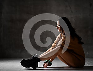 Young blonde fashion woman sitting on floor in brown knitted blouse