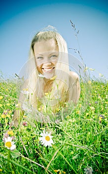 Young blonde on meadow with camomile