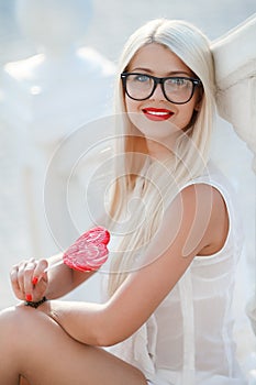 Young blonde woman with heart shaped lollipop