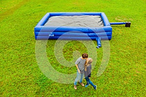 Young couple on the background of a large inflatable blue trampoline on green grass