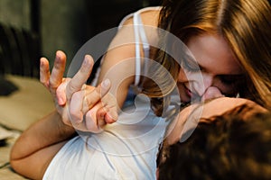 Young couple in love lying in bed in hotel, embracing on white sheets, close up