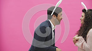 Young sexy couple on pink background. With hackneyed ears on the head. During this, rabbit jumps recreate the movements