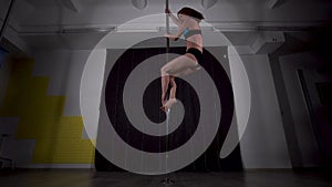 Young sexy girl in a bathing suit spinning on a pole in the dark