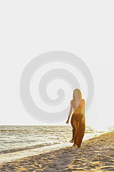 Young sexy girl on the beach at sunset in a swimsuit