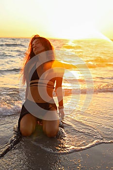 Young sexy girl on the beach at sunset in a swimsuit