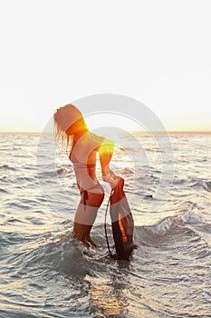 Young sexy girl on the beach at sunset in a swimsuit