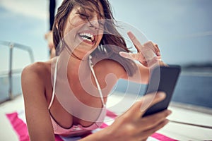 A young sexy girl is having a video chat on a smartphone while enjoying a sunbath. Summer, sea, vacation