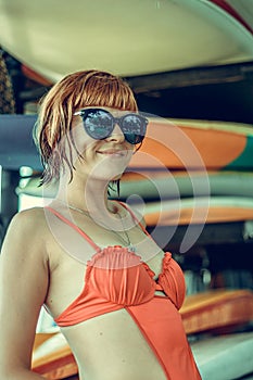 Young girl in red swimsuit - surfer with surf board posing on the Nusa Dua beach, tropical Bali island, Indonesia