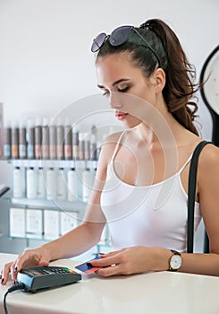 Young sexy girl using payment terminal keypad in shop or supermarket