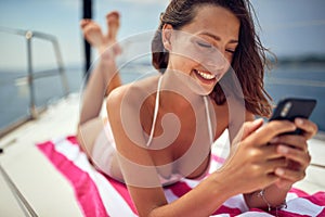 A young sexy girl is watching a content on a smartphone and enjoying a sunbath. Summer, sea, vacation