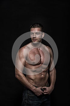 Young handsome athletic man with naked torso on dark background
