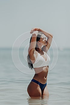 Young latin woman in bikini walking in the water along the beach