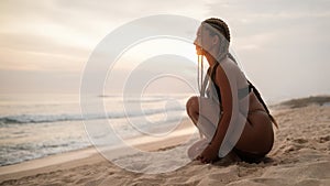 Young sexy Latina woman with braids on her head and in a bikini on the beach