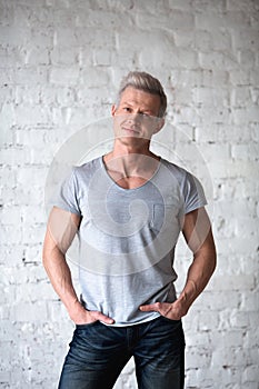 Young sexy men bodybuilder athlete studio portrait in loft on the background of white brick wall. Handsome guy model in