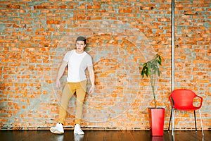 Young men bodybuilder athlete,studio portrait in loft, guy model in white T-shirt and brown trousers