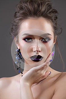 Young sexy model with professional makeup, perfect skin, high volume hairstyle. Violet eye arrows, dark violet lips