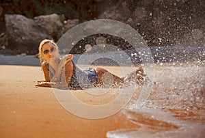 Young sexy and relaxed blond woman in one piece swimsuit lying on the sand looking at sea enjoying summer holidays at beautiful
