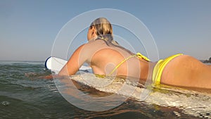 Young sexy woman in bikini is surfing in the sea. Surfer girl in ocean.