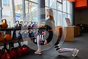 Young sexy woman during fitness workout at gym. Exercises with dumbbells. Squats and lunges.