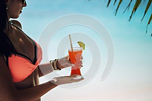 Young sexy woman with fresh drink in hands on beach, drink on exotic vacation