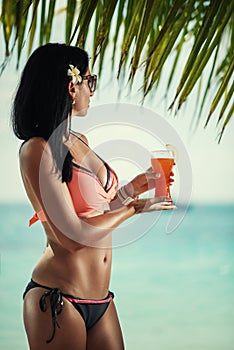 Young sexy woman with fresh drink in hands on beach, drink on exotic vacation