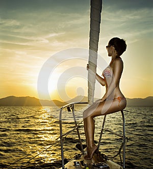 Young woman on her private yacht at sunset