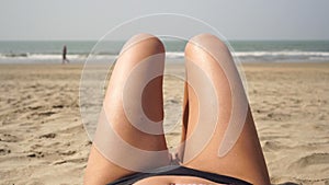 Young sexy woman sunbathes on a sea beach, hips and legs close-up