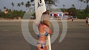 Young sexy woman surfer on the beach with a surfboard