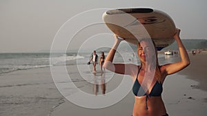 Young sexy woman surfer on the beach with a surfboard