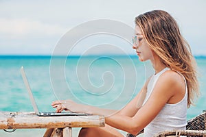 Young woman using laptop on the beach. Freelance work photo