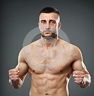 Athletic fighter posing on gray